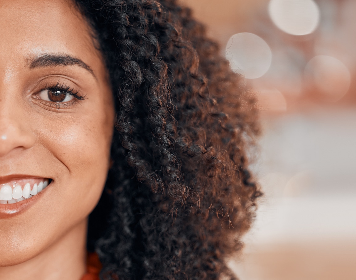 A partial view of a woman’s face as she smiles brightly at the camera with a full, healthy set of teeth.