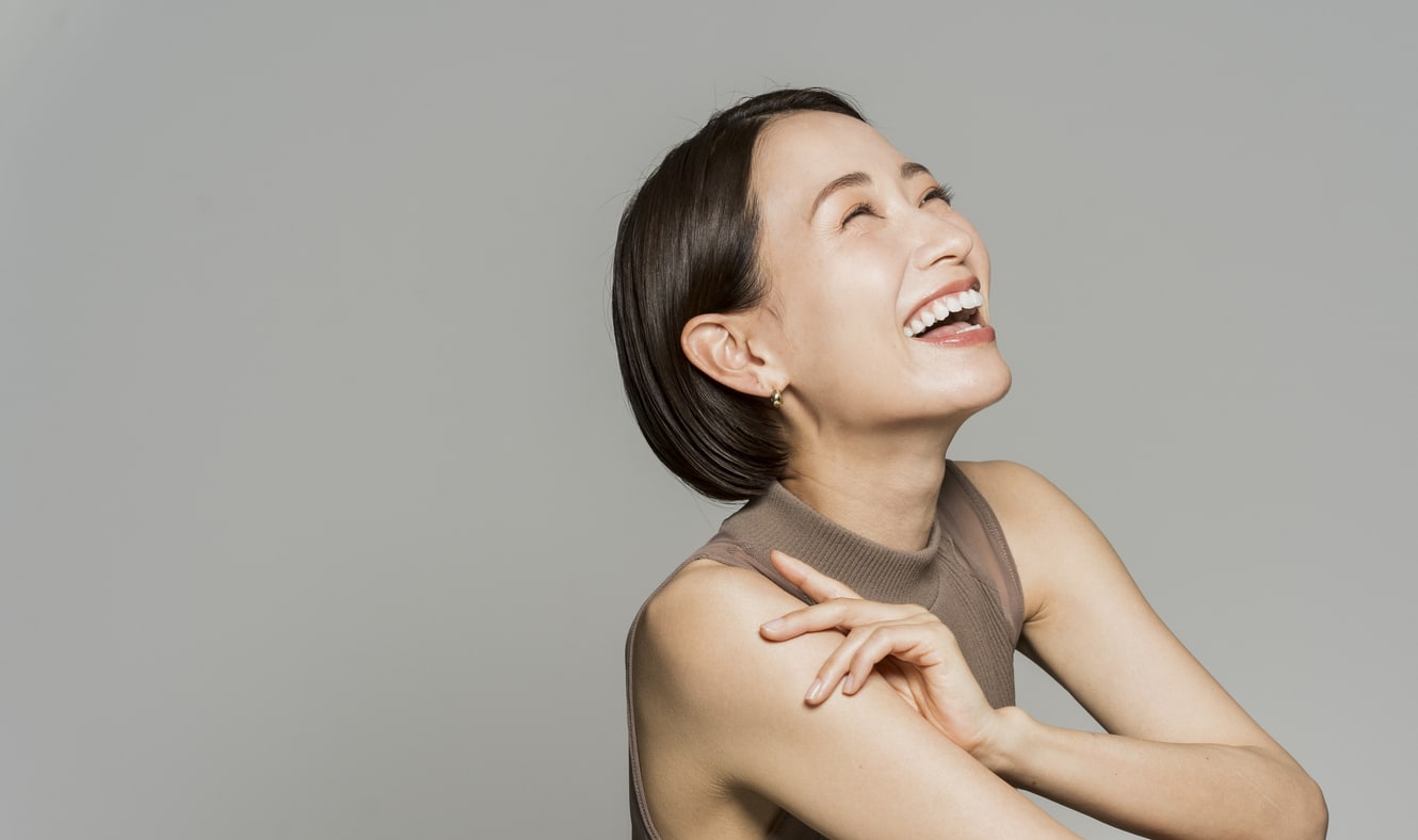 A woman with short, brunette hair smiles with confidence after receiving teeth whitening treatment, a cosmetic dentistry procedure offered by Koch Aesthetic Dentistry.